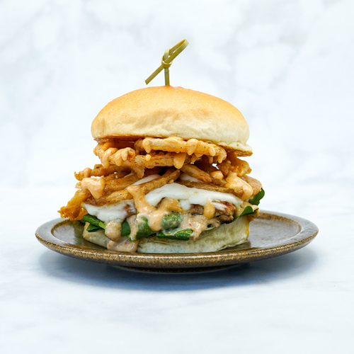 Grilled Chicken Burger - Marinated chicken breast, Rocca leaves, mozzarella cheese, sundried aioli sauce, fried onion rings and spicy sauce served in a homemade bun.