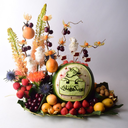 Kharouf Al Eid 14 - Eid Al Adha kharouf design watermelon carving with fresh fruits and fresh erygium and pins flowers on a tray. Size: 35x35