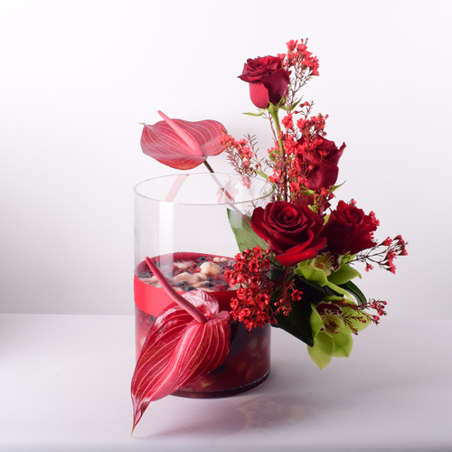 Habib Al Umor 15 - Berries
  salad on a glass vase decorated with fresh roses, anthorium and cymbidium
  flowers.