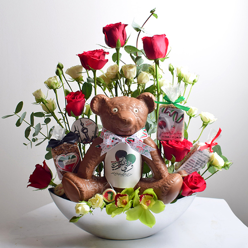 al khayal 14 - acrylic
  tray with a decoration of fresh roses, cymbidium and gerbera flowers with
  rice crispy, Big teddy bear chocolate and chocolates.