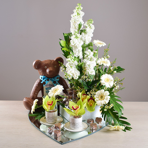 Baby boy 1 - Baby
  Boy mirror tray with Chocolate Bear, Coffee cups set, chocolates, and a
  decoration of fresh cymbidium, gerbera, wax flower and Matola Flowers.