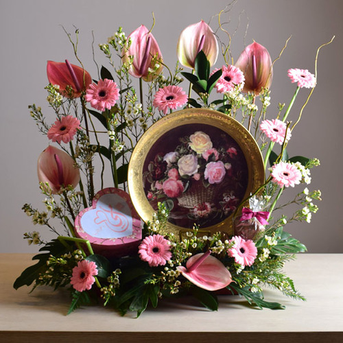 janati 1 - Gold
  painted decorative plate display with a decoration of fresh gerbera, wax
  flowers and anthorium flowers with 1 heart box of chocolates inside.