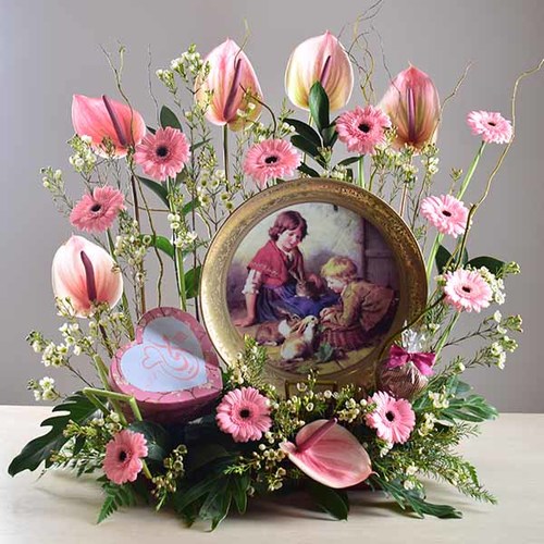 janati 4 - Gold
  painted decorative plate display with a decoration of fresh gerbera, wax
  flowers and anthorium flowers with 1 heart box of chocolates inside.