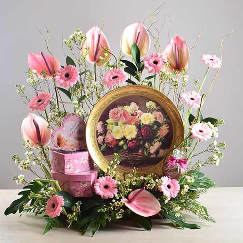 janati 7 - Gold
  painted decorative plate display with a decoration of fresh gerbera, wax
  flowers and anthorium flowers with 3 heart box of chocolates inside.