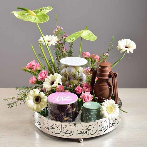 Ramadan Yijmana 42 - silver
  round tray with fanoush chocolate, dates with nuts and kuwaiti sweets inside
  the glass jar and tarbush with a decoration of fresh gerbera, anthorium,
  roses and wax flowers.