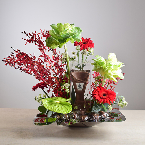 Ramadan Yijmana 53 - Silver
  tray with Mubhkar Chocolate,  Ramadan
  Chocolates, and a decoration of fresh anthorium, brasica, gerbera and wax
  flowers.