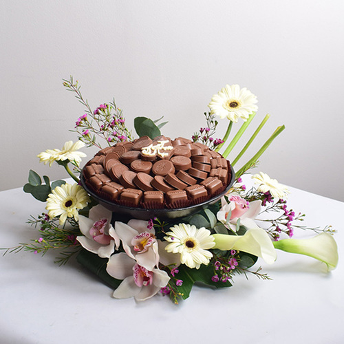 eid adhha & haj mabror 17 - tray
  of chocolates with a decoration of fresh cymbidium, calla, gerbera and wax
  flowers.