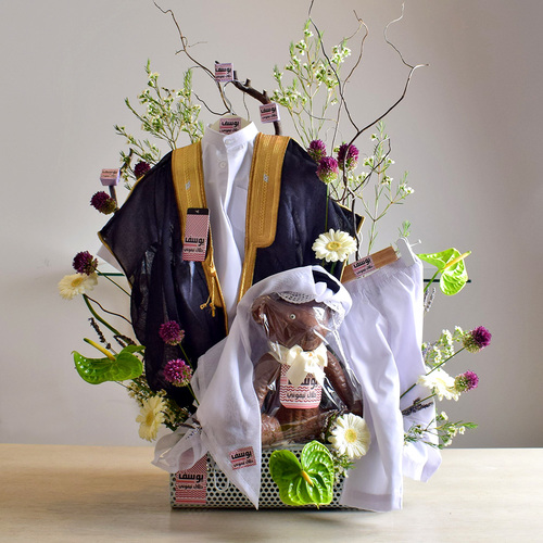 Bisht Gift 2 - Baby
  Boy Bisht Robe cloth with baby name on a teddy bear chocolate and a
  decoration of fresh anthorium, gerbera, wax flower and baby allum on a silver
  box.