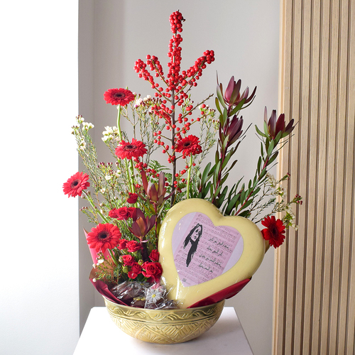 Anta Auomri 16 - golden
  bowl with big heart chocolates, small chocolates and a decoration of fresh
  gerbera, baby roses, hyperecum and wax flowers.