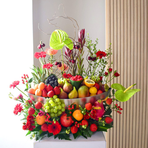 Anta Auomri 29 - An
  acrylic tray with a decoration of gerbera, roses, Anthorium, safari and wax
  flowers with assorted mixed fruits.