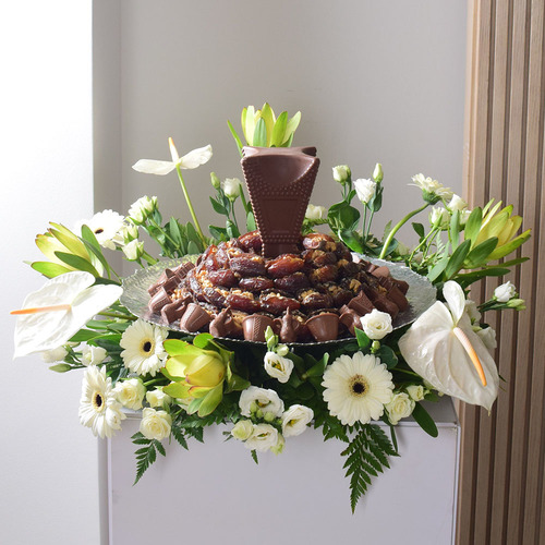 Me & You 14 - 2 kilo
  of dates with nuts with 1 mubkhar design chocolates on a silver color tray
  with a decoration of fresh gerbera, anthorium ,and lisianthus flowers.