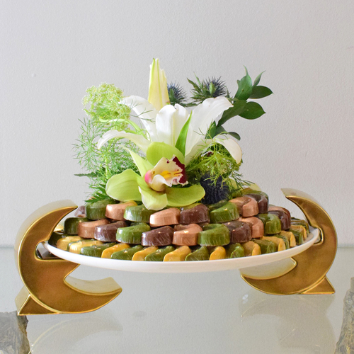 Helal Al Eid - Moon
  shape stand on a&nbsp; ceramic plate with
  Eid Mubarak Chocolates and a decoration of fresh casa blanca, cymbidium,
  hemomodius&nbsp; & earygium flower.