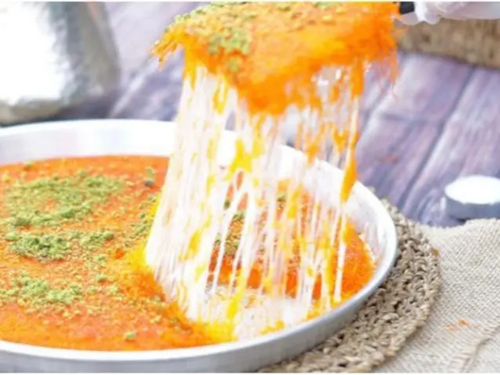 Kunafa Nabulsi With Cheese - Orange konafa with nabulsi cheese served with pistachio and syrup