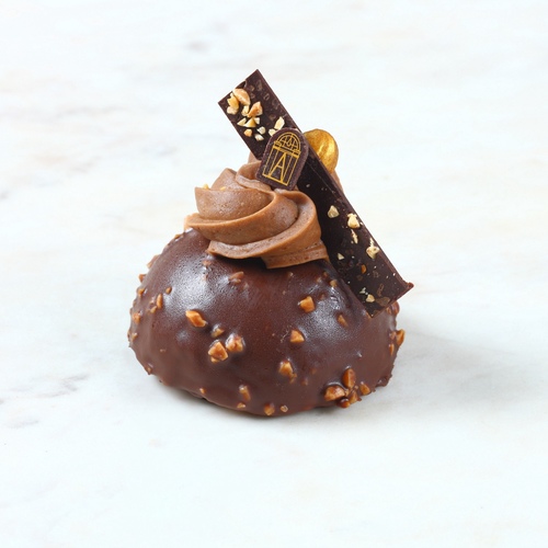 Rocher - The Rocher is made to delight praline lovers who Fall for its different textures:&nbsp;crunchy&nbsp;hazelnut praline mousse, dacquoise topped with a generous milk chocolate&nbsp;Chantilly and&nbsp;garnished with&nbsp;a&nbsp;dark chocolate bar.