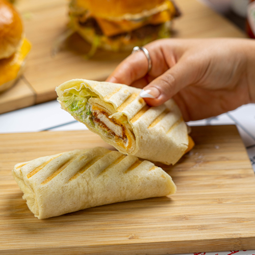 Tortilla Chicken Wrap Sandwich - Fried chicken tender, lettuce, honey mustard sauce, sliced cheddar cheese, and tortilla bread.