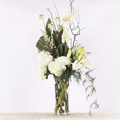 Elizabeth - White flowers arrangement of hydrangeas, lily, anthurium, matthiola with green leaves in a tall glass vase. 
 H 100 cm x W 50 cm.