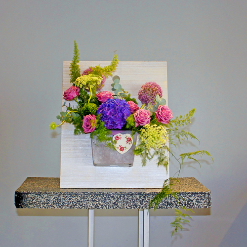 Purple Lush - A shades of purple and green bouquet of roses, hydrangea and visnaga arranged in vase attached on wooden board.