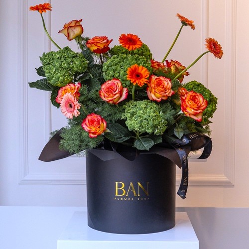 Green and Orange Bliss - A chic black box brimming with bright green and orange flowers, perfect for any occasion.