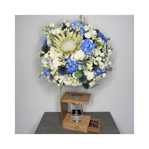 Blue Blossom - This wooden basket, brown color contains king protea, eustoma, rise flower and mix of baby roses, and hydrangea with Belgian chocolates.
Height: 90cm Width: 57cm Sell by: Quantity