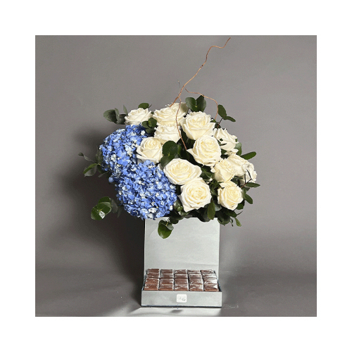 Wintry Blue - Mirror vase with white roses, blue hydrangea and Belgian chocolate 
Height: 58cm  Width: 37cm  Sell by: Quantity