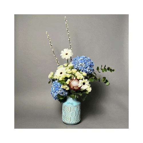 Blue Sea - A light blue vase with blue hydrangea, white baby roses and gerbera with red protea.
 Height: 60cm  Width: 95cm  Sell by: Quantity