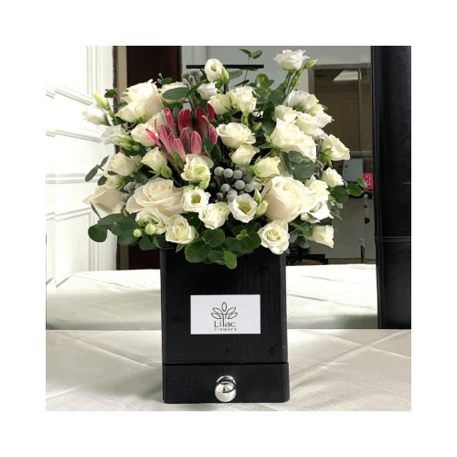 White Dream - A black wooden box with black handle full of mixed white flowers and green leaves with Belgian chocolates. 
Height: 45cm  Width: 25cm  Sell by: Quantity