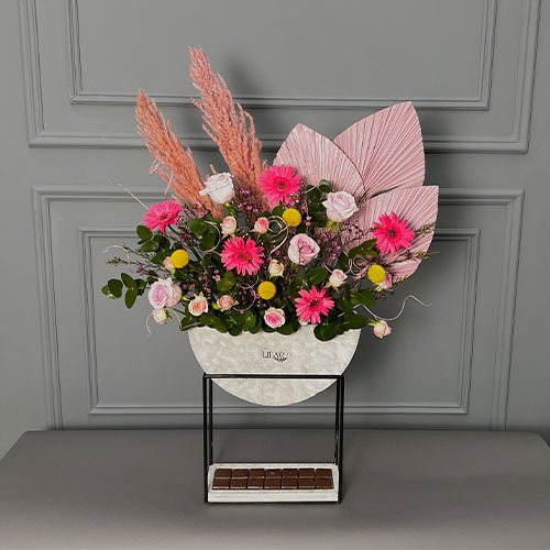 Sunrise - Hight stand vase with fuchsia gerbera, pink rose, pink baby rose and Belgian chocolate.  
 Height 100  width 65