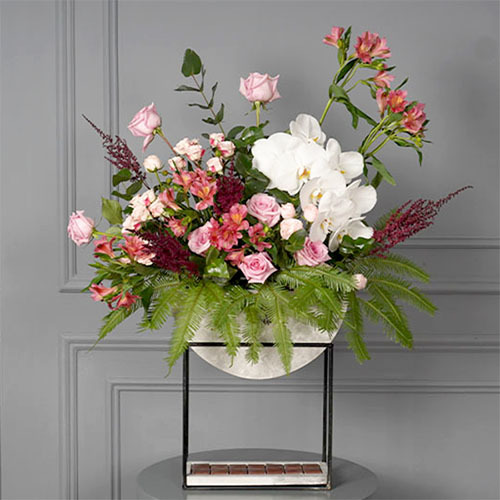 Mamma Mia - wooden vase with stand contains a mix of roses, baby roses, white orchid, alstroemeria and Belgian chocolate. Height 93  Width 80