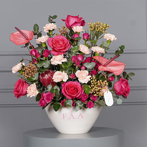 Amelia - white vase contain pink rose, pink anthurium, red protea with carnation.  writing on the item 5 characters.  Height 55 Width 53