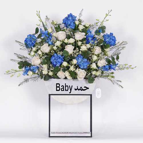 Hamad - wooden stand contains blue hydrangea, white rose, white wax, white baby rode, baby orchid and Belgian chocolate  Height 95 Width 89