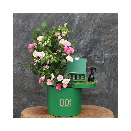 Greeno - Green box contains pink and fuchsia baby roses, pink carnations, green leaves with box of chocolate and 150ml spray.  Height: 60cm  Width: 45cm