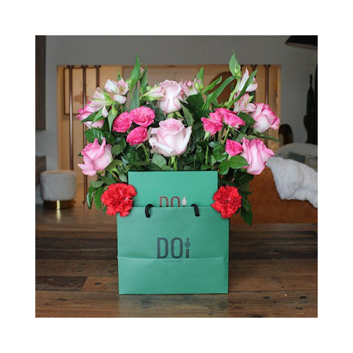 Budapest - Green bag contains pink roses, fuchsia baby roses, pink alstroemeria, green leaves with box of chocolates. Height: 40cm Width: 30cm