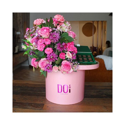 Mallorea - Pink box contains pink roses, fuchsia baby roses and purple chrysanthemum flowers, green leaves with box of chocolates. Height: 70cm Width: 35cm