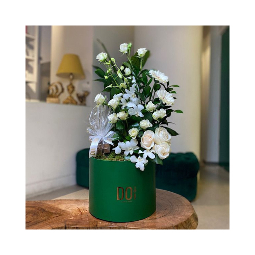 Shaika - Green box contains white garabera green leaves erynguim with white baby roses with chocolate. Height: 40cm Width: 20cm