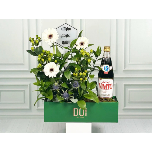 Vimto - Green box contains white grabera , green hypericum, green leaves with Vimto and acrylic. Height: 50cm width: 40cm