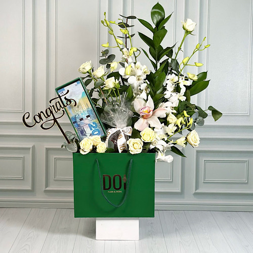 Graduate 1 - Green bag contains white baby orchid, white baby roses, white cymbidium and green leaves with chocolate, money box and acrylic. Height: 50cm Width: 30cm