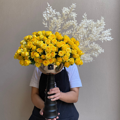 Crowned Sunshine - Yellow baby roses crowned with white ruscus in a long gold stand 
 H *Flower kind and color may slightly
differ based on availability.