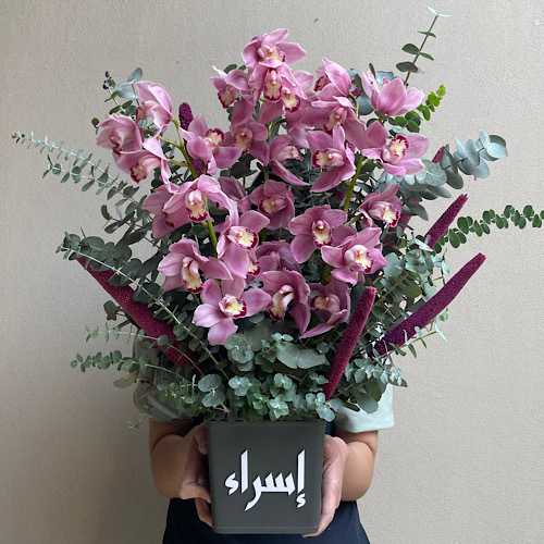 Fleurette - Magenta Love - Dark pink cymbediums arranged in a customized grey leather vase *Write the desired name in the message box*Flower kind and color may slightly
differ based on availability.