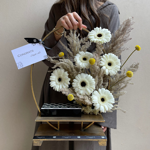 The gold stand I - An arrangement of flowers in a gold stand with art deco box of chocolates  
 H 50cm*Flower kind and color may slightly
differ based on availability.