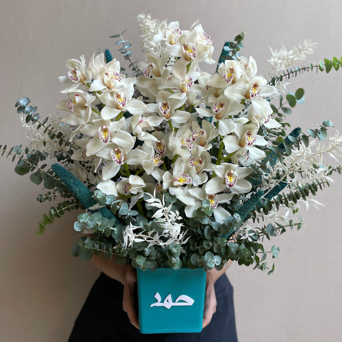 Sky Blue - White Cymbediums arranged with white ruscus in a customized blue leather vase *Write the desired name in the message box*Flower kind and color may slightly
differ based on availability.