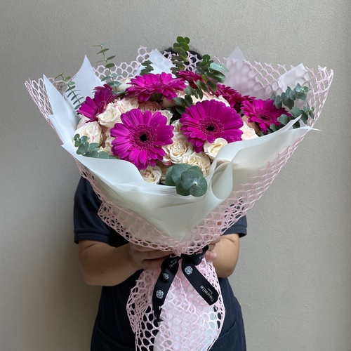 Bouquet de fleur - An arrangement of flowers wrapped in pink mesh wrapping paper. *Flower kind and color may slightly differ based on availability.