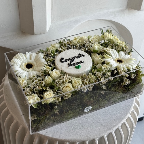 White Glow I - A clear rectangular box with cover filled with baby roses and gerbera and a mini cake. *write the name on the cake in the message box L35 H12