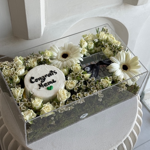 White Glow II - A clear rectangular box with a cover filled with baby roses, gerbera and a mini cake. * write the desired name on the cake in the message box L35 H 12