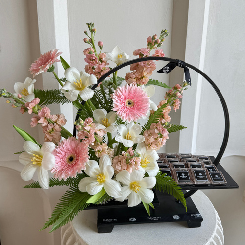 Fleurette - Ring of joy - An arrangement of tulips, mithiola and gerbera with chocolates in a black stand