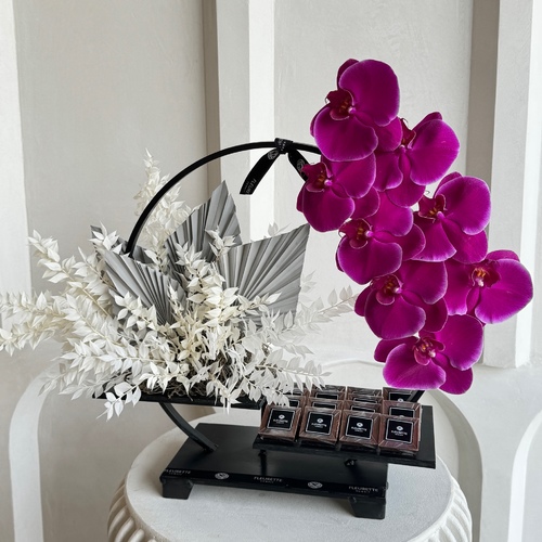 Fleurette - Ring of Phalaenopsis - A black ring stand with orchids and chocolates 
 L 38cm * W 40cm*Flower kind and color may slightly
differ based on availability.