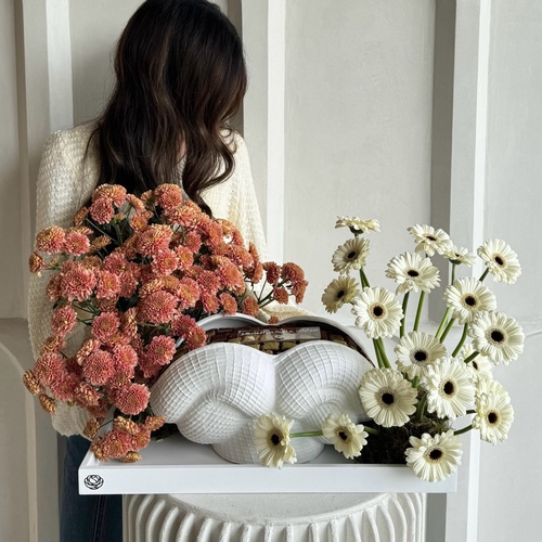 Spiritual - A decorative white ceramic vase in a big white tray decorated with flowers and rangina with pistachio, cinnamon and caramel*Flowers color and kind may slightly differ based on availability *Notice: order will be delivered within 24hrs.