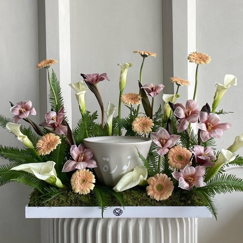 Playful blooms - An arrangement of calla, tulips and gerbera with 21cm candle in a white tray *Please write the desired name on the candle in the message box *Flowers kind and color may slightly differ based on availability