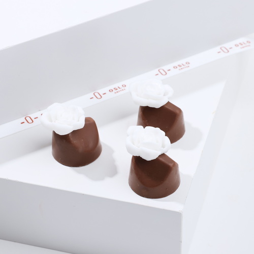 Tropical flower - A beautiful piece of fine chocolate, filled with a tropical blend of mango and passion fruit, adorned with an elegant white flower, and meticulously crafted in Oslo’s factories.