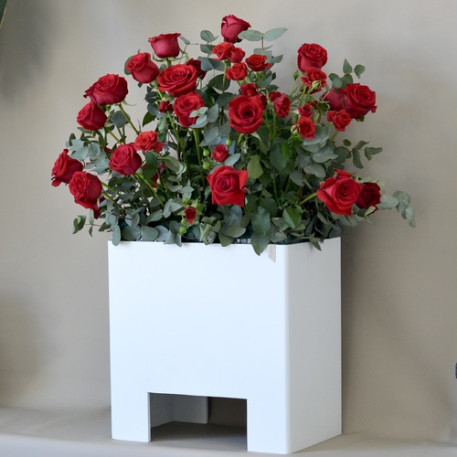 Nera - A wooden stand that contains fresh red roses.