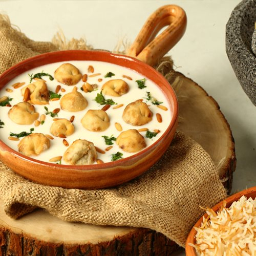 Lokmat Beit - Shishbarak - meat dumpling in garlic yogurt toped with pine & coriander served with vermiceli rice